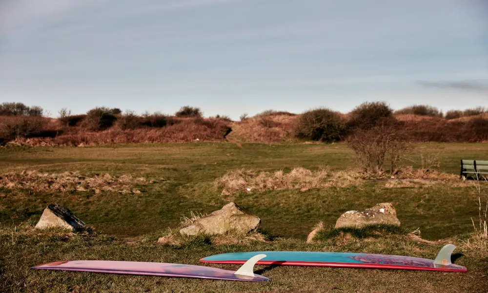 two-surf-boards-lying-on-grass-near-the-beach
