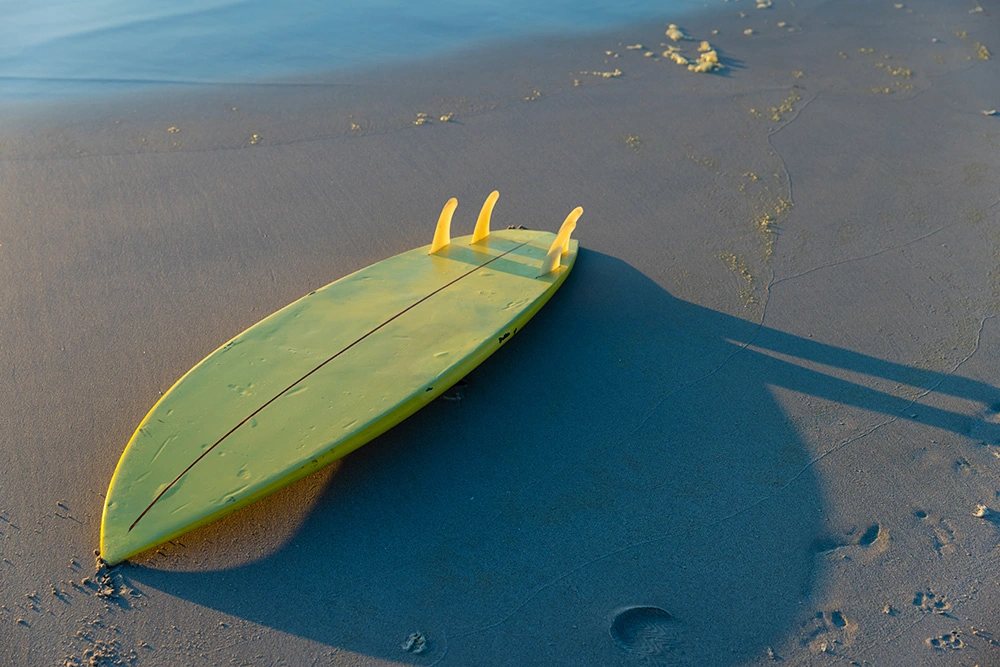 yellow-surfboard-on-sandy-beach